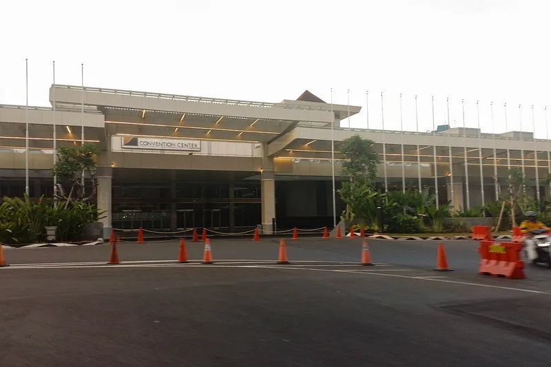 Fasad dan lobi utama gedung Jakarta Convention Center (JCC) Senayan dengan pilar balok krem, kanopi drop-off berlampu geometris, serta signage CONVENTION CENTER berlatar kaca transparan